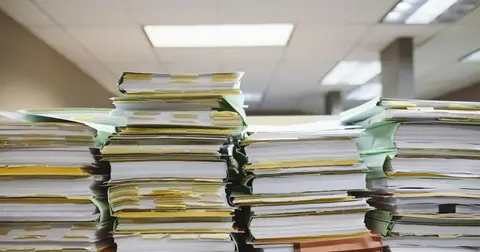 Tall stacks of paper documents and file folders in an office