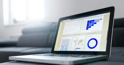 Open laptop showing a spreadsheet with charts on a sofa