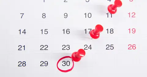 Calendar page with red pushpins marking several dates