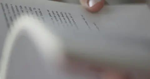 Close-up of a hand turning the pages of printed text